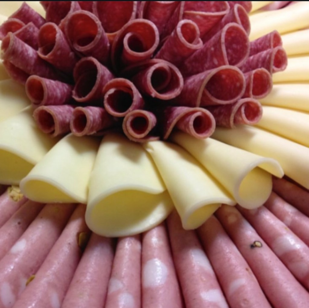 Charcuterie arrangement with rolled deli meats and cheese